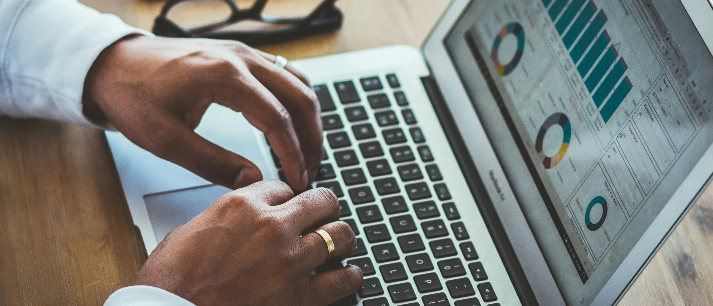 Hands at a laptop showing a financial dashboard