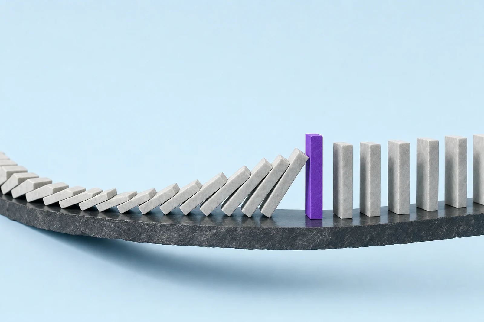 A run of pale stone dominoes caught mid-fall and stopped by one upright glowing violet block